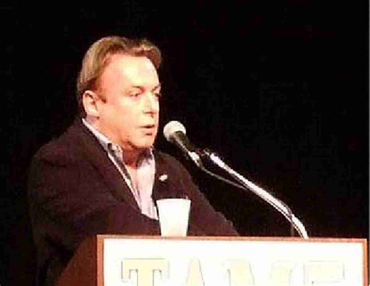 Christopher Hitchens Passionately Speaking On Stage With A Stack Of Books Beside Him. Christopher Hitchens And His Critics: Terror Iraq And The Left